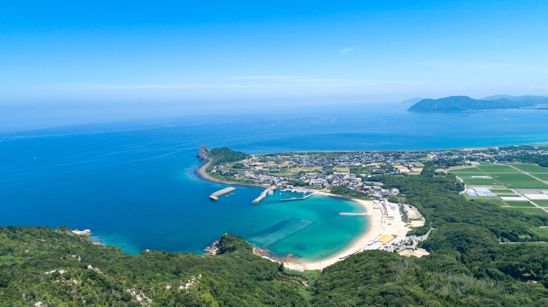 青い海と白い砂浜が広がる海岸の町を上空から撮影した風景