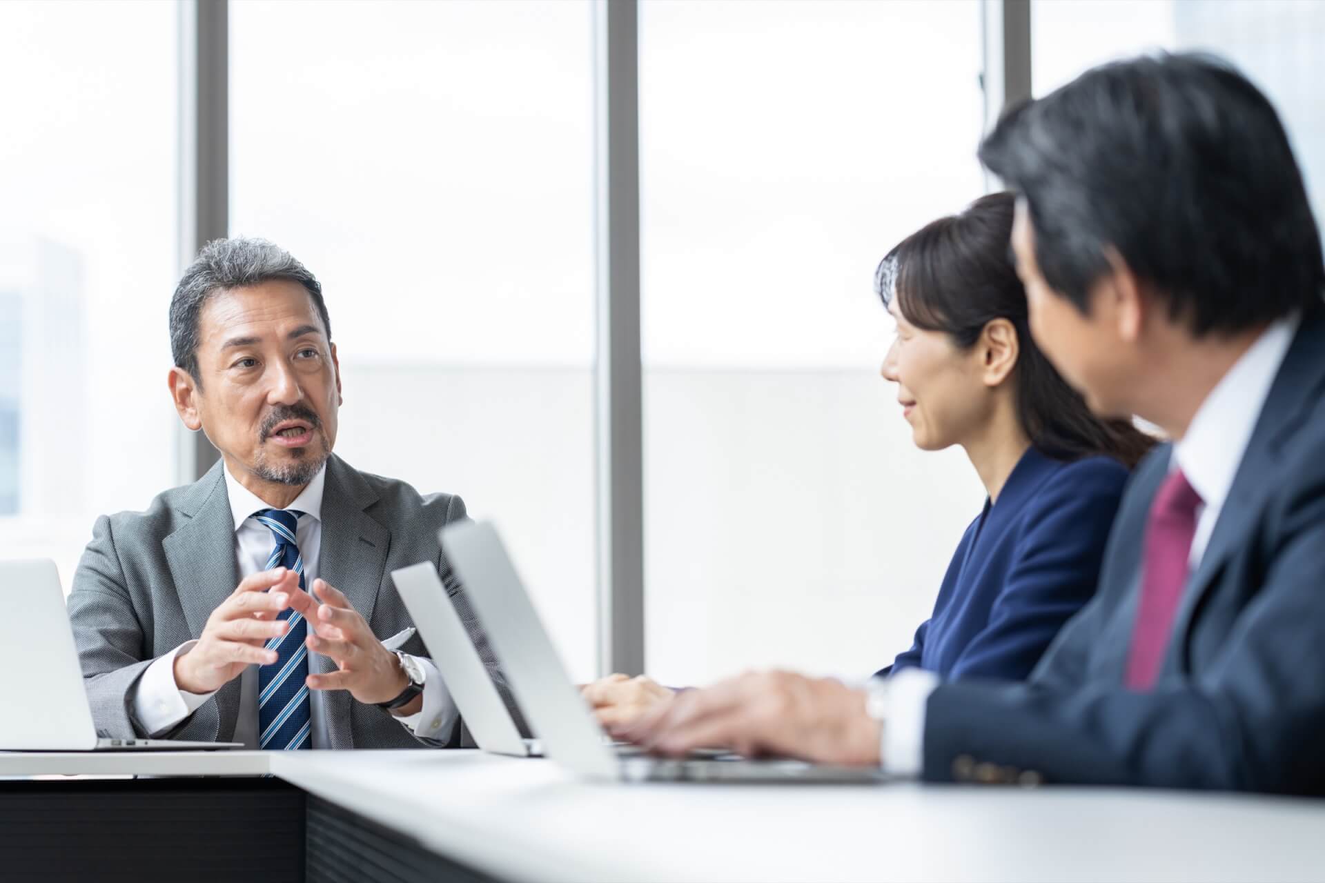 会議で社員と話し合う経営者