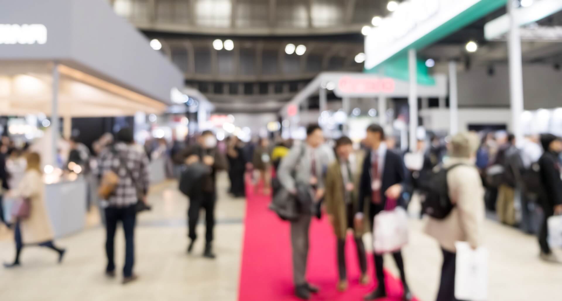 展示会場の通路を歩きながら、両側に並ぶブースを見て回る来場者たち