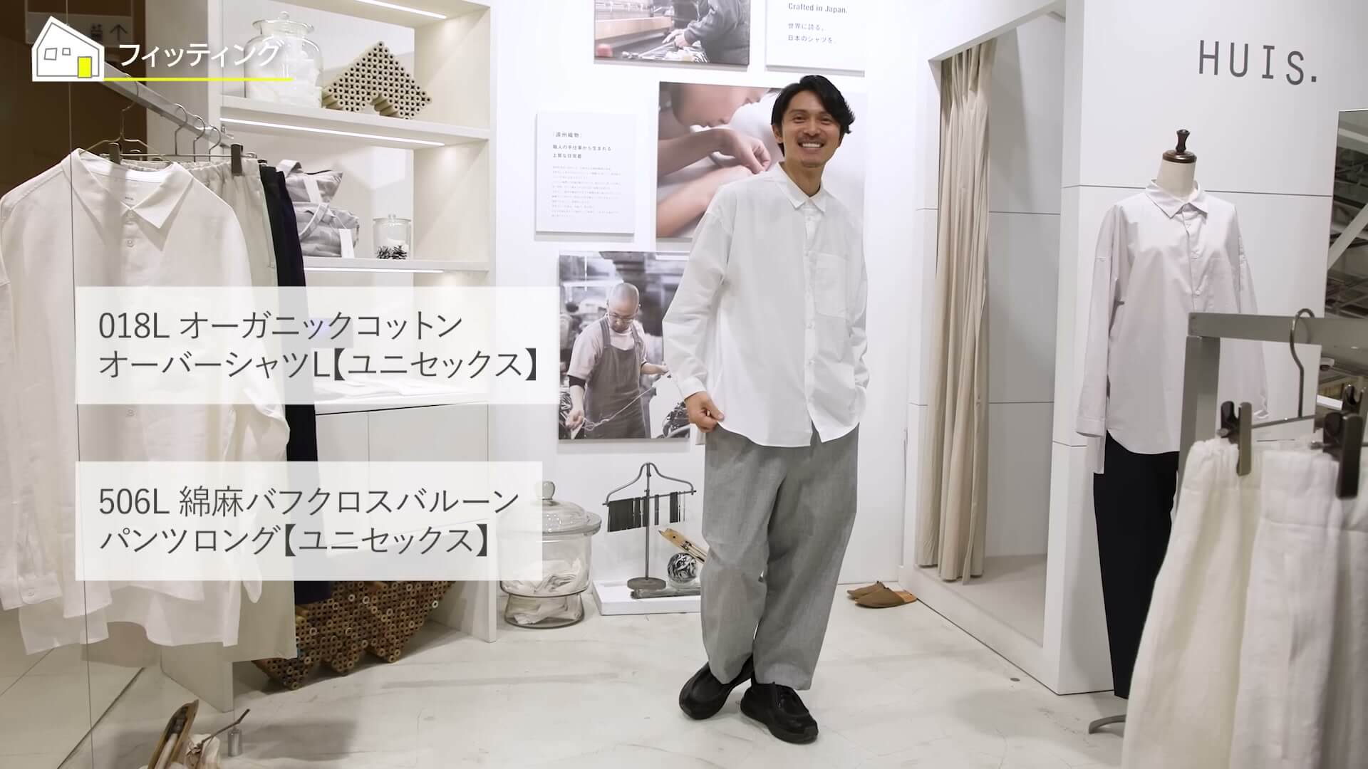 ショールームで、オーバーシャツとバルーンパンツの着こなしを見せる場面