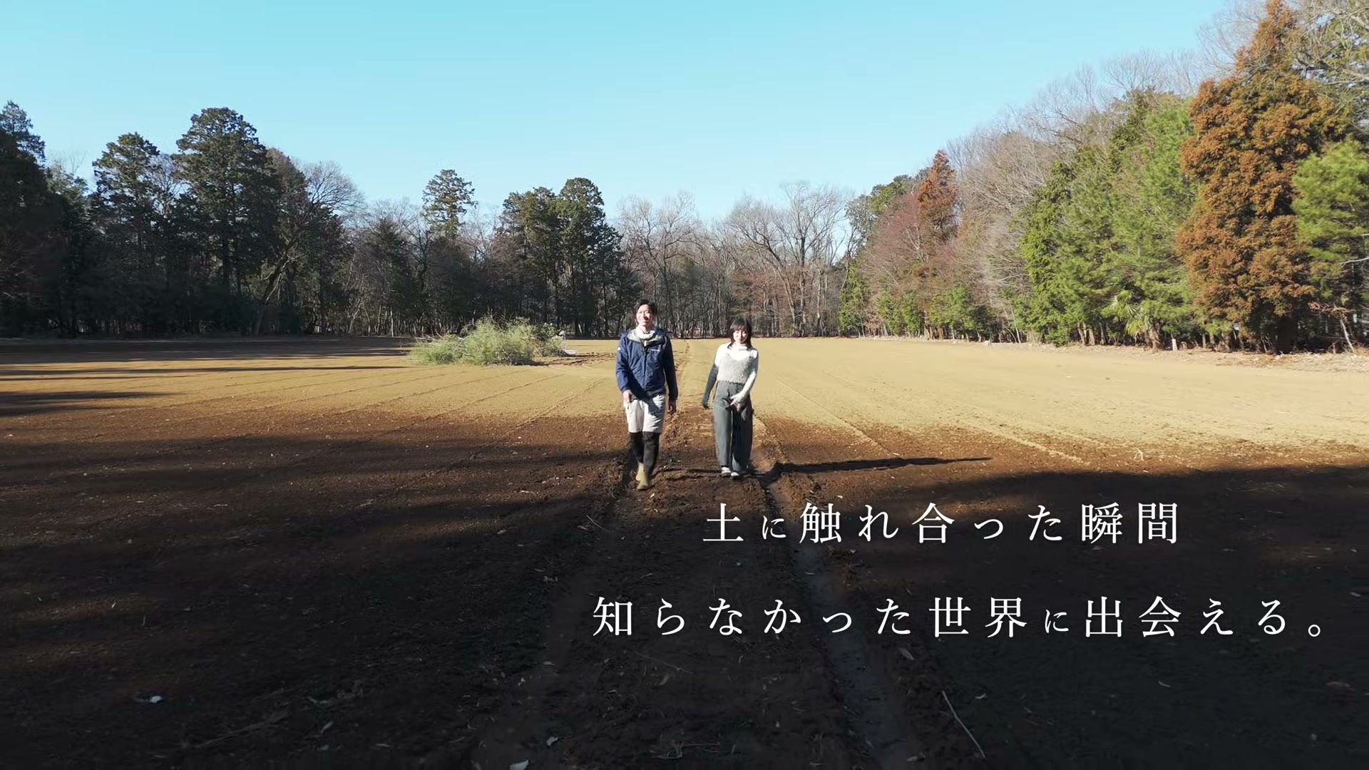畑を歩く2人。「土に触れ合った瞬間 知らなかった世界に出会える。」のテロップ