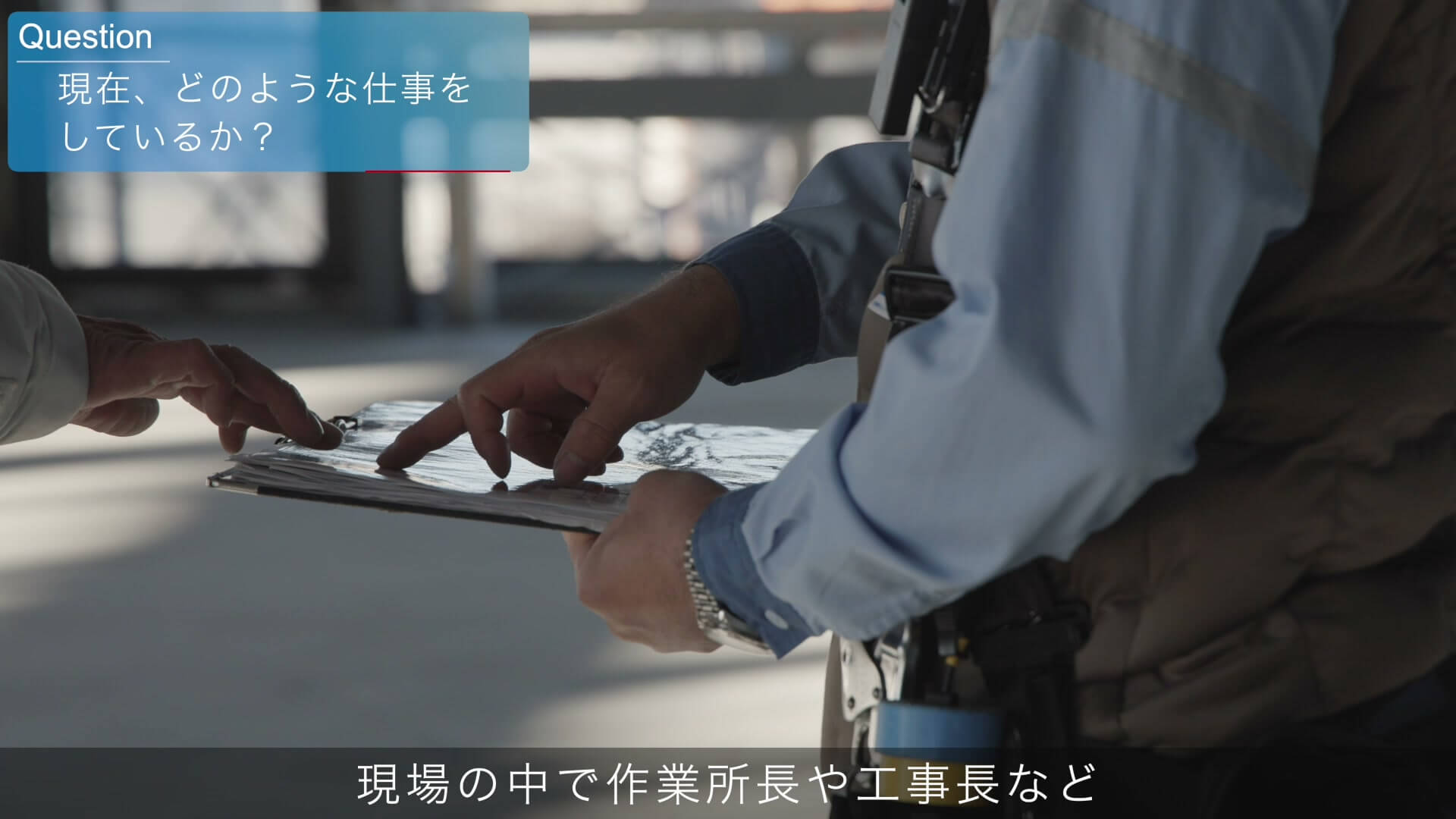 建設現場でクリップボードの書類を指さして確認する手元