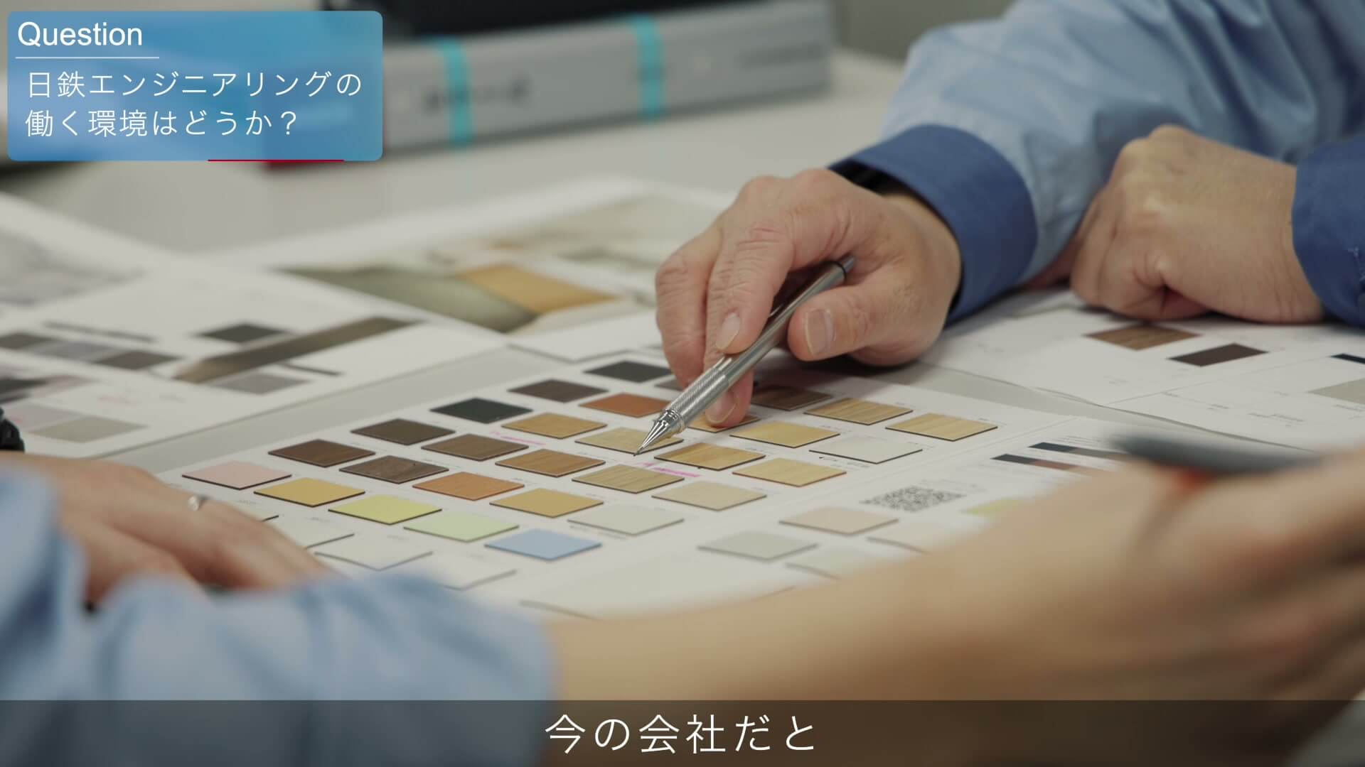 色見本を前に、ペンで仕上げ材を指して打ち合わせをする手元