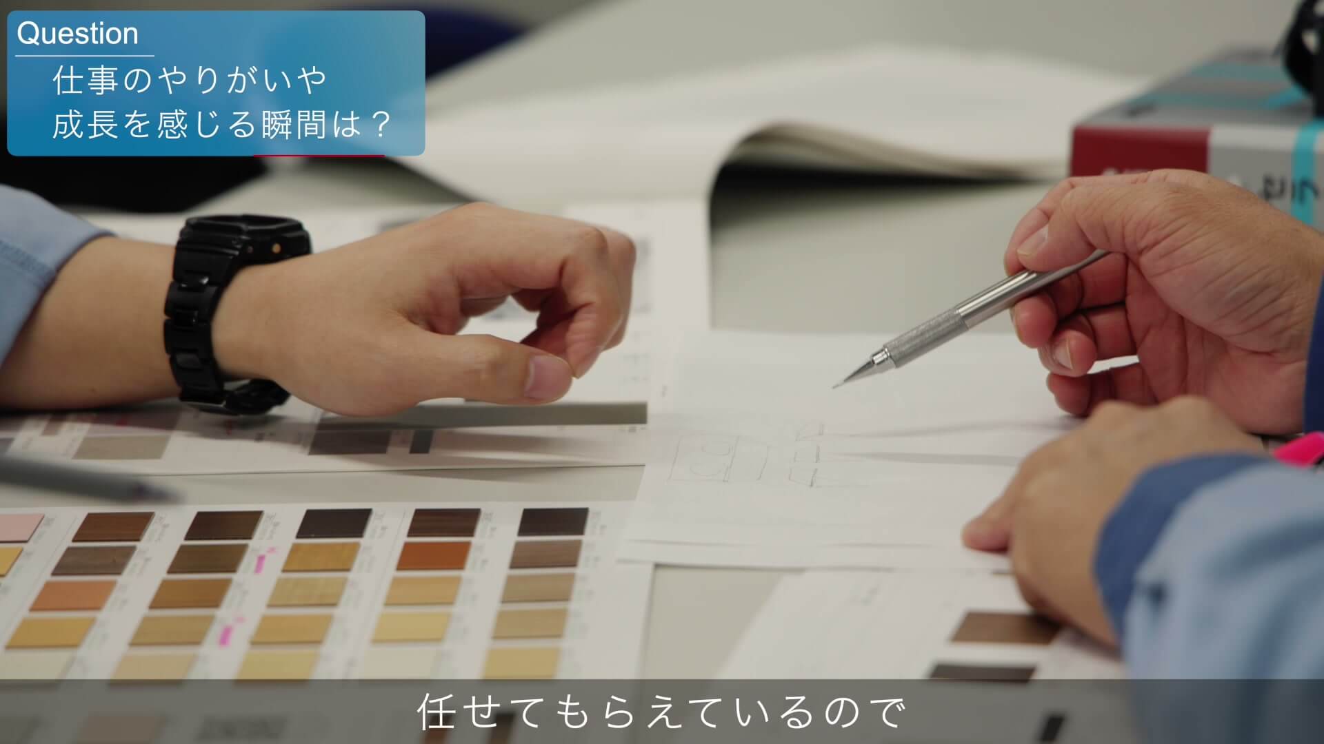 色見本と図面を前に、ペンを持って説明する手元