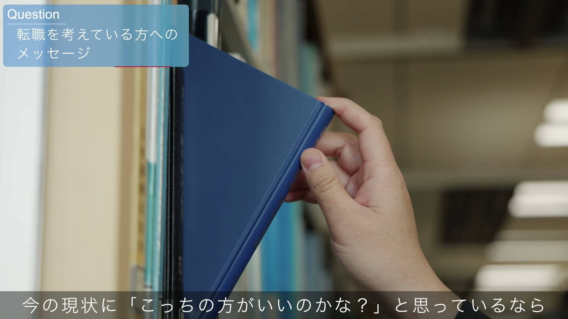資料室の棚から青いファイルを取り出す手元