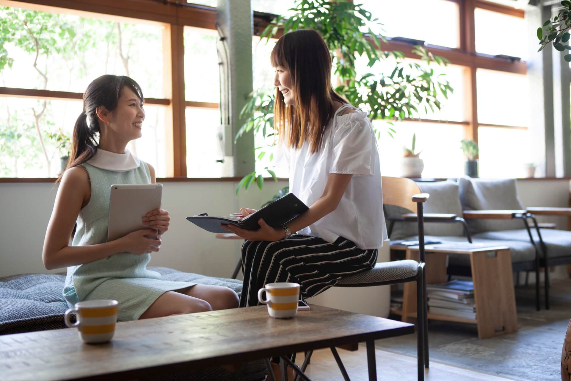 明るいラウンジで資料を見ながら打ち合わせをする2人の女性