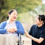 並木道で車椅子のご入居者と笑顔で話す介護スタッフ