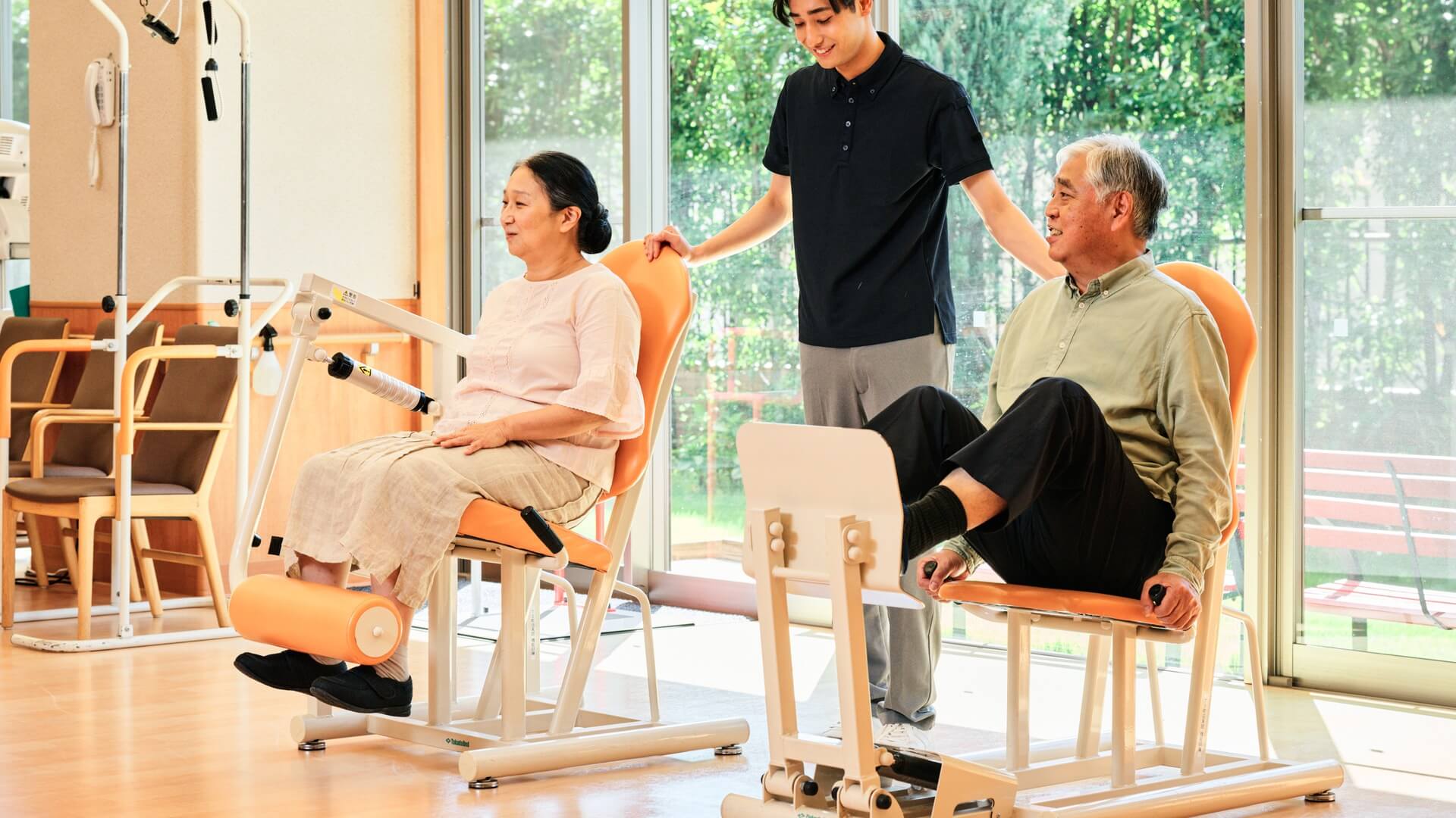 機能訓練室のトレーニングマシンでご入居者を見守るスタッフ