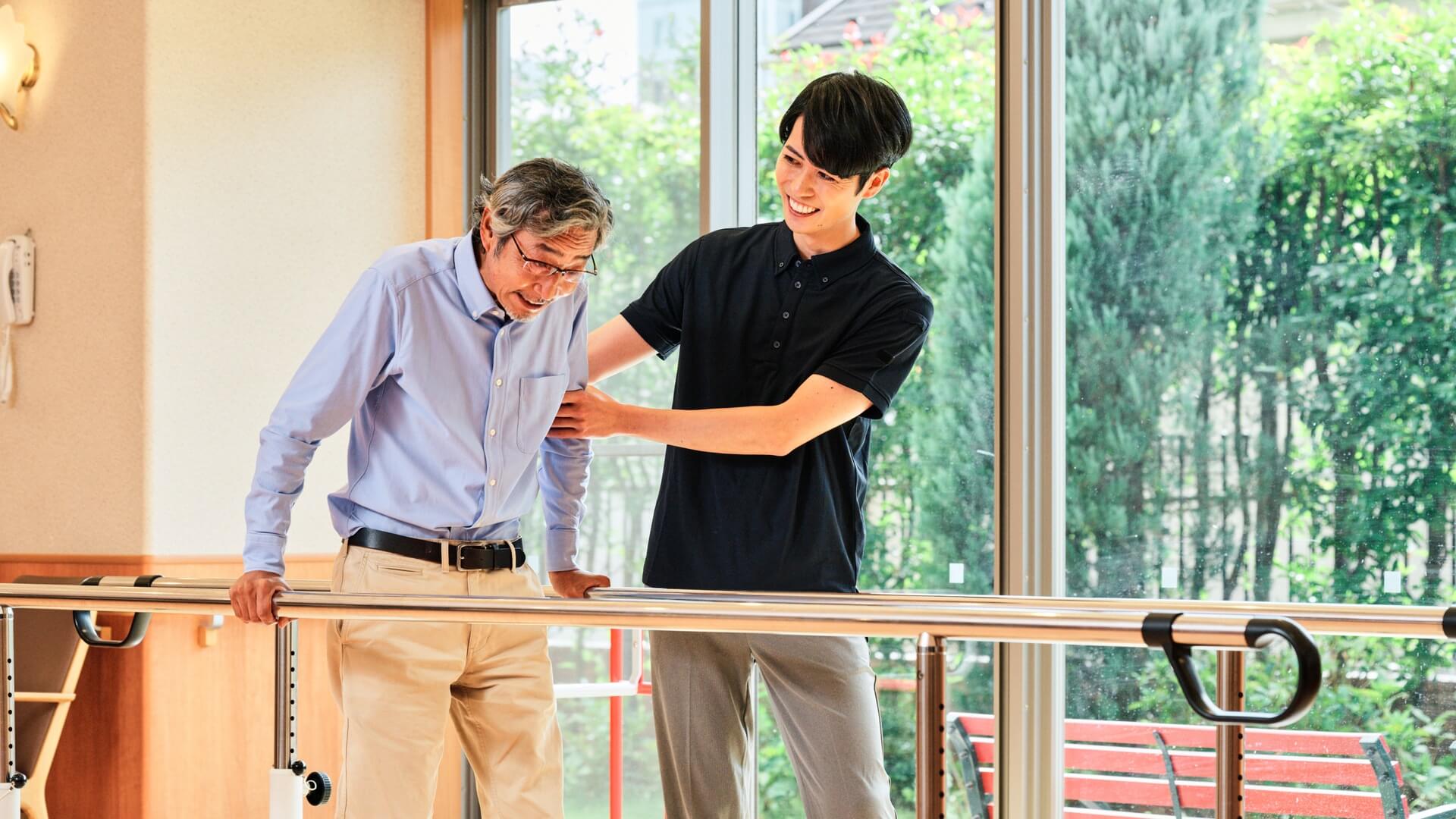 平行棒での歩行練習を支えるスタッフ