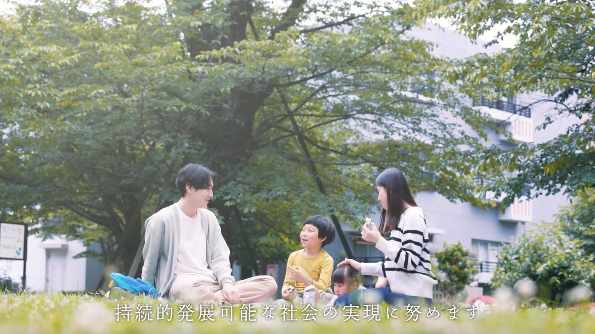 木陰のレジャーシートでピクニックをする家族