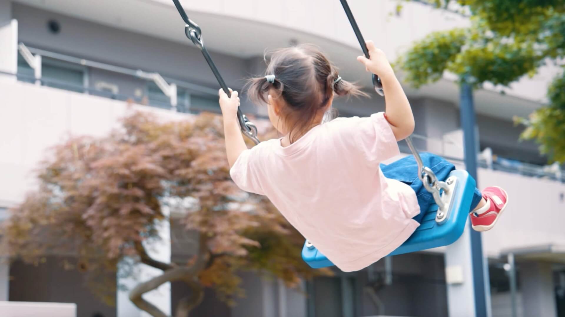 住棟の前の公園で、ブランコをこぐ女の子の後ろ姿